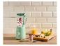 Groene blender met fruit en yoghurt, naast een glas smoothie en fruit op een houten plank.