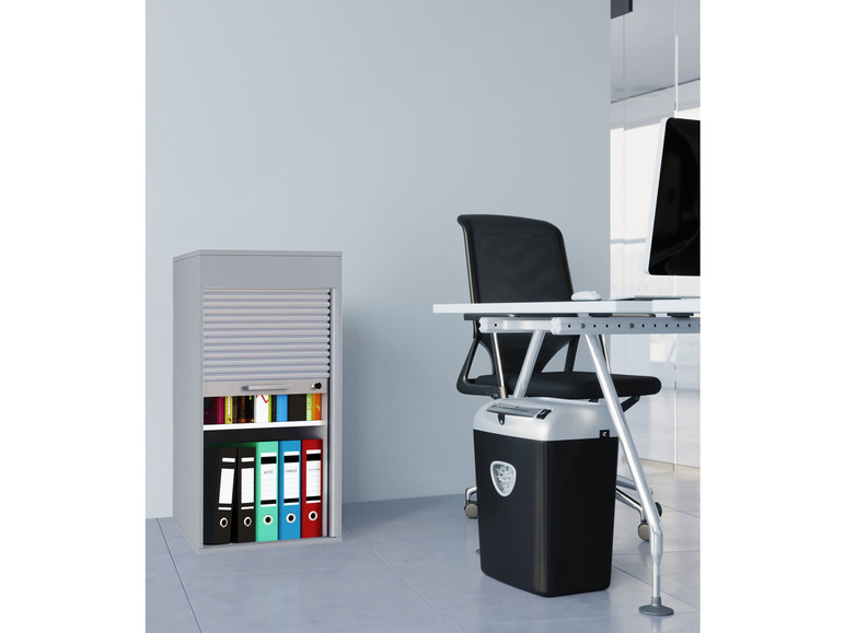 Een grijze metalen kast met een roldeur, een zwarte papierversnipperaar en een bureaustoel in een kantoor.