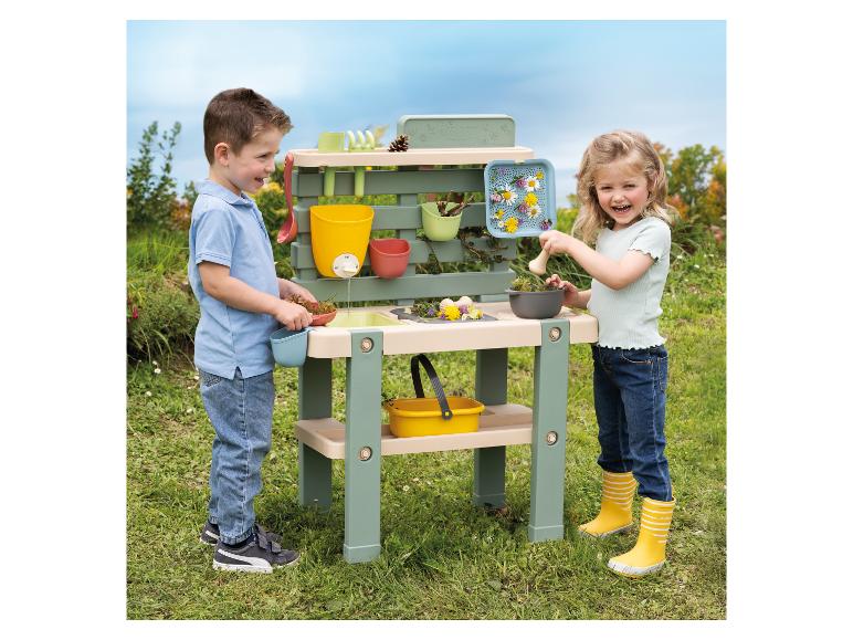 Twee kinderen spelen buiten met een Smoby speelgoedtuintafel.