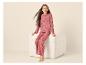 Meisje in roze pyjama met zwarte harten, zittend op een witte poef.