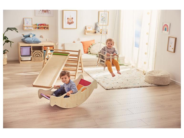 Kinderen spelen met houten glijbaan, schommel en schommelstoel in speelkamer.