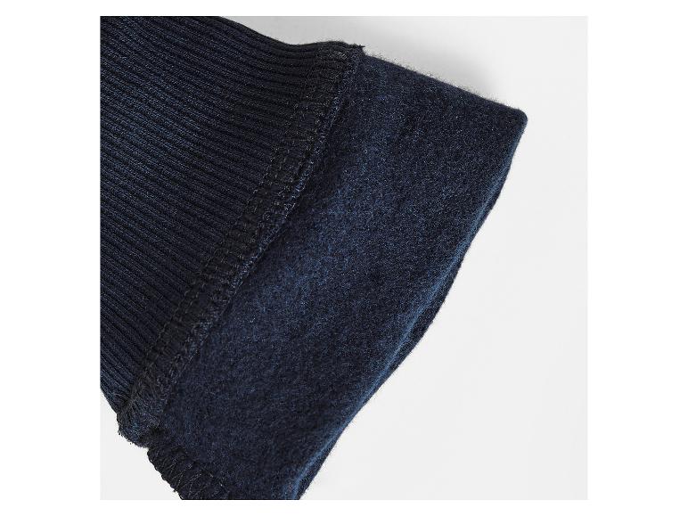 Detail van de manchet van een donkerblauw, lang mouwen jas.