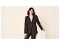 Vrouw in zwarte blazer en leren broek lacht naar de camera.