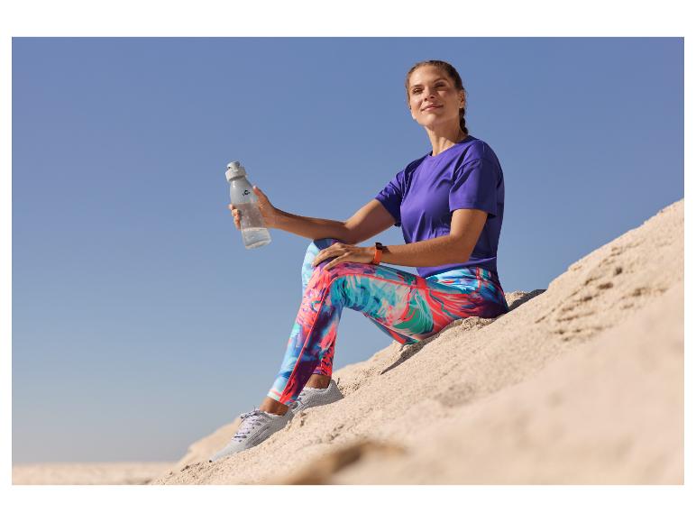 Vrouw in sportkleding, gekleurde leggings en waterfles. Close-up.