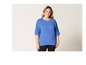 Een vrouw draagt een blauwe blouse met pofmouwen.