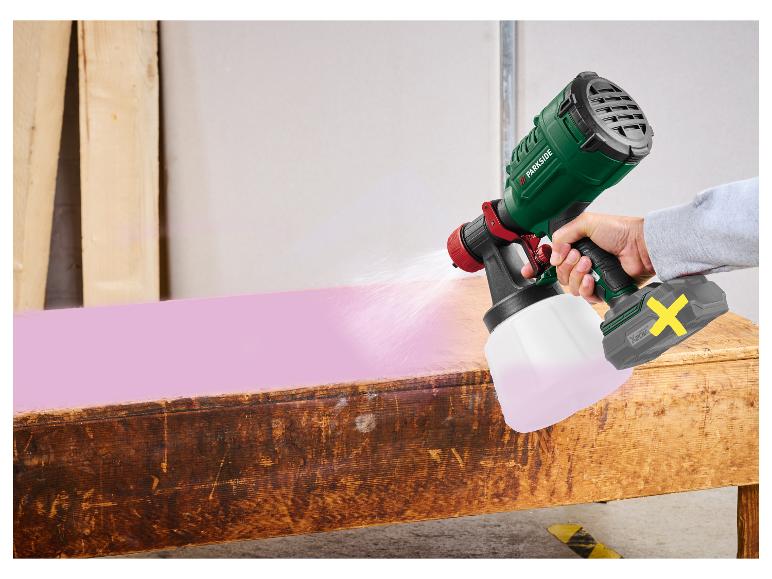 Draadloos verfspuitpistool spuit roze verf op een houten tafel.