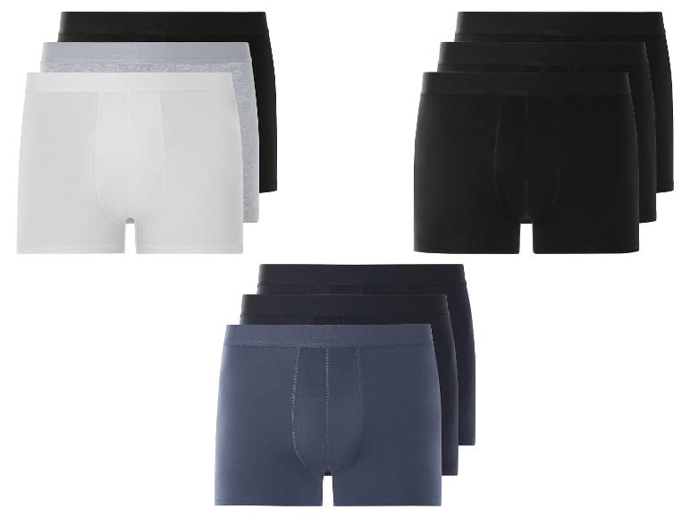 Drie pakjes met drie boxershorts in wit, grijs en zwart.