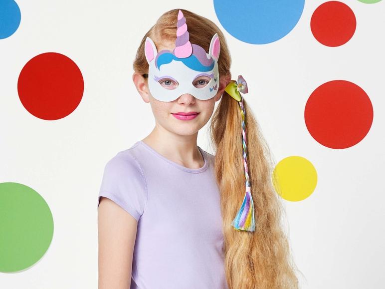 Een meisje draagt een unicorn masker met een regenboog haarband.