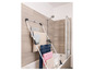 Een wit wasrek in een badkamer met handdoeken en kleding.