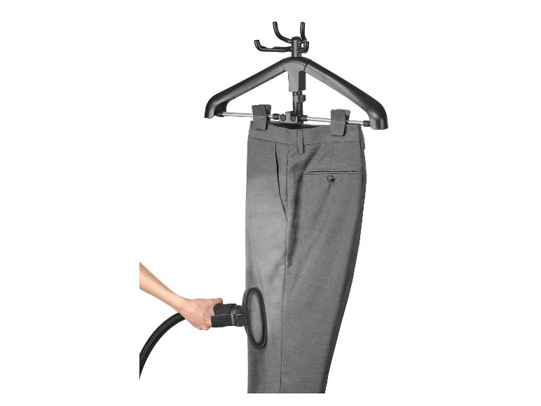 Grijze broek op een hanger, gestoomd met een handstomer.