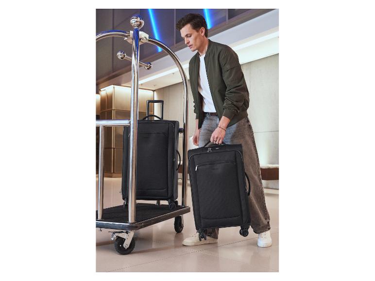 Een man tilt twee zwarte softcase koffers op naast een bagagewagen.