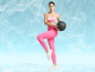 Een vrouw in roze leggings en een sportbeha houdt een medicijnbal vast.