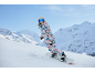 Vrouw in kleurrijk snowboardpak en helm snowboardt in de bergen.