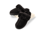 Zwarte pantoffels met imitatiebont op een witte kubus.