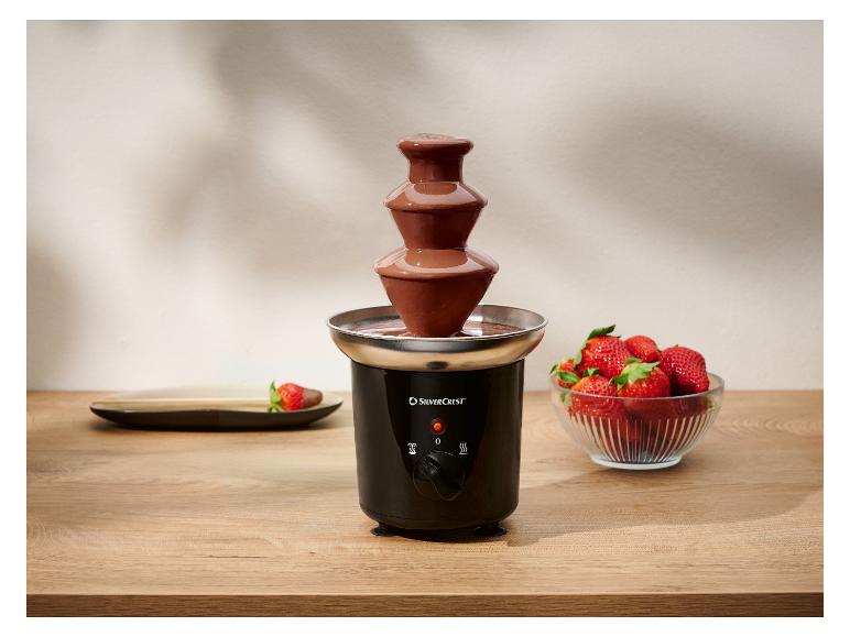 Zwarte chocoladefontein met verse aardbeien op een houten tafel.