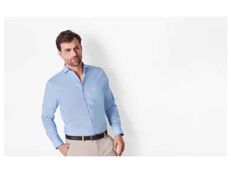 Man in lichtblauw overhemd en beige broek met een bruine riem