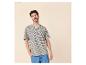 Man in beige en marineblauw gestreept T-shirt, blauwe jeans, hand in zak.