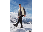 Man in gewatteerd vest en sportbroek in besneeuwd landschap.