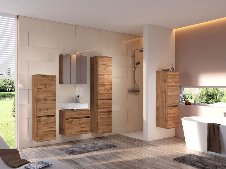 Badkamer met houten badkamermeubels, een spiegelkast en een bad.
