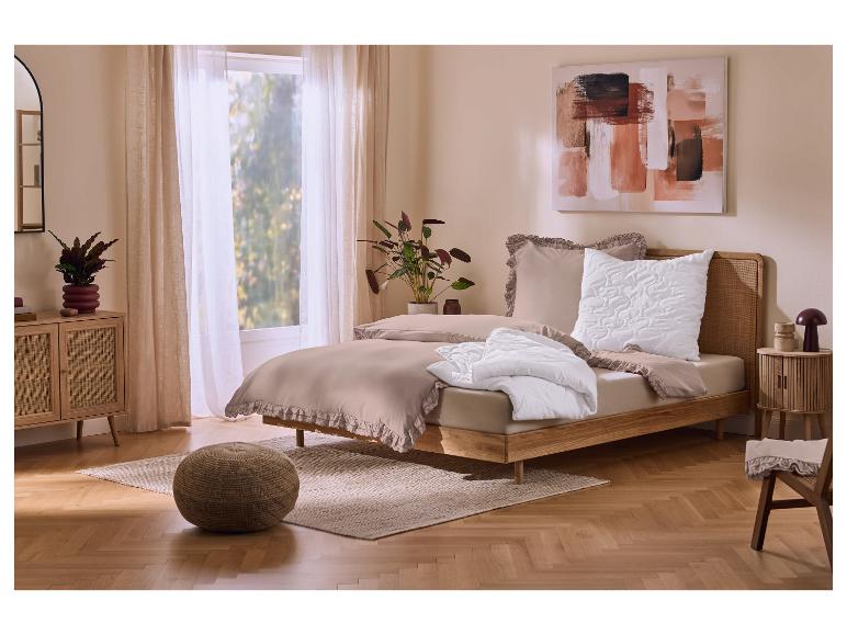 Slaapkamer met beige beddengoed met ruches, houten bed en nachtkastje, en een schilderij.