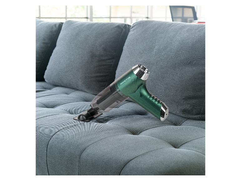 Groene Invictus handstofzuiger reinigt een grijze bank.
