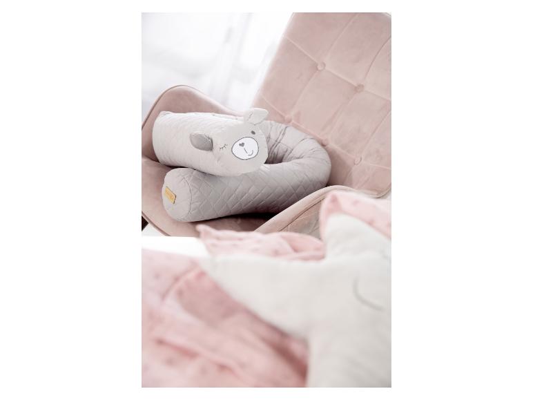 Grijze teddybeer-vormige voedingskussen op een roze fauteuil met een roze deken.