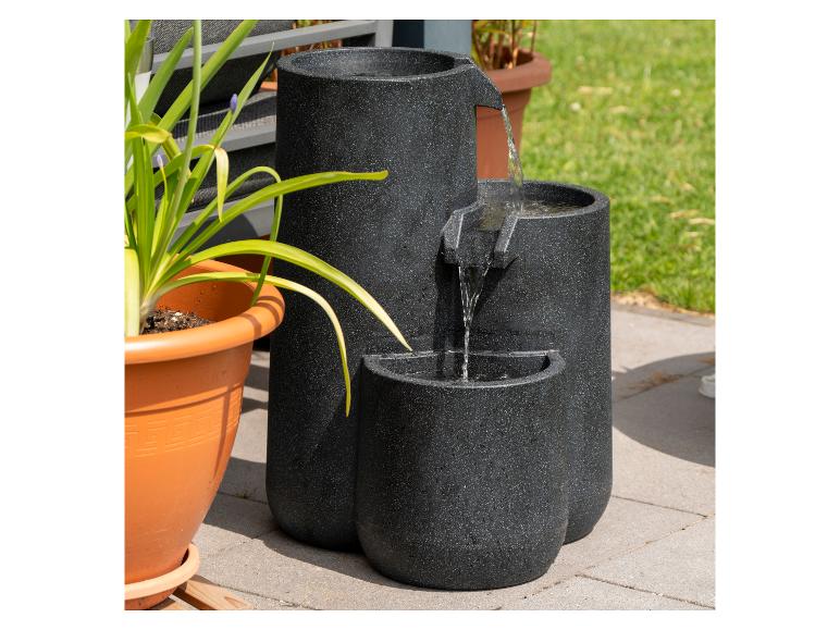 Gelaagde waterpartij met stromend water, naast een potplant op een terras.