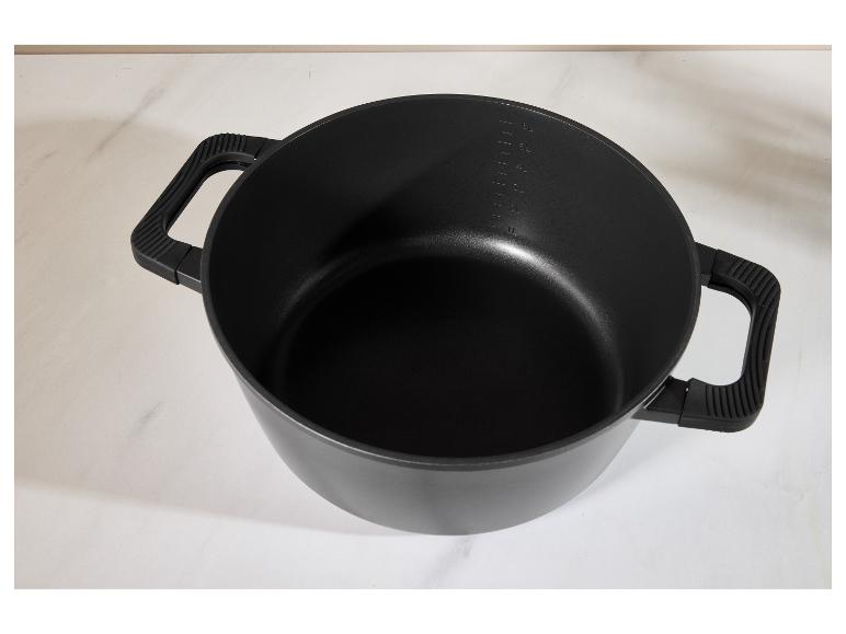 Zwarte kookpan met handvatten en maatstreepjes op een wit oppervlak.