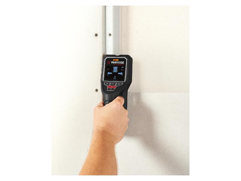 Wanddetector in de hand, scant een muur op een metalen profiel.