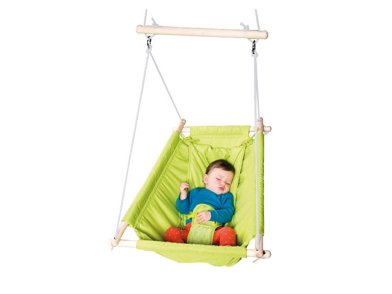 Een baby slaapt in een groene hangschommel met veiligheidsgordels.