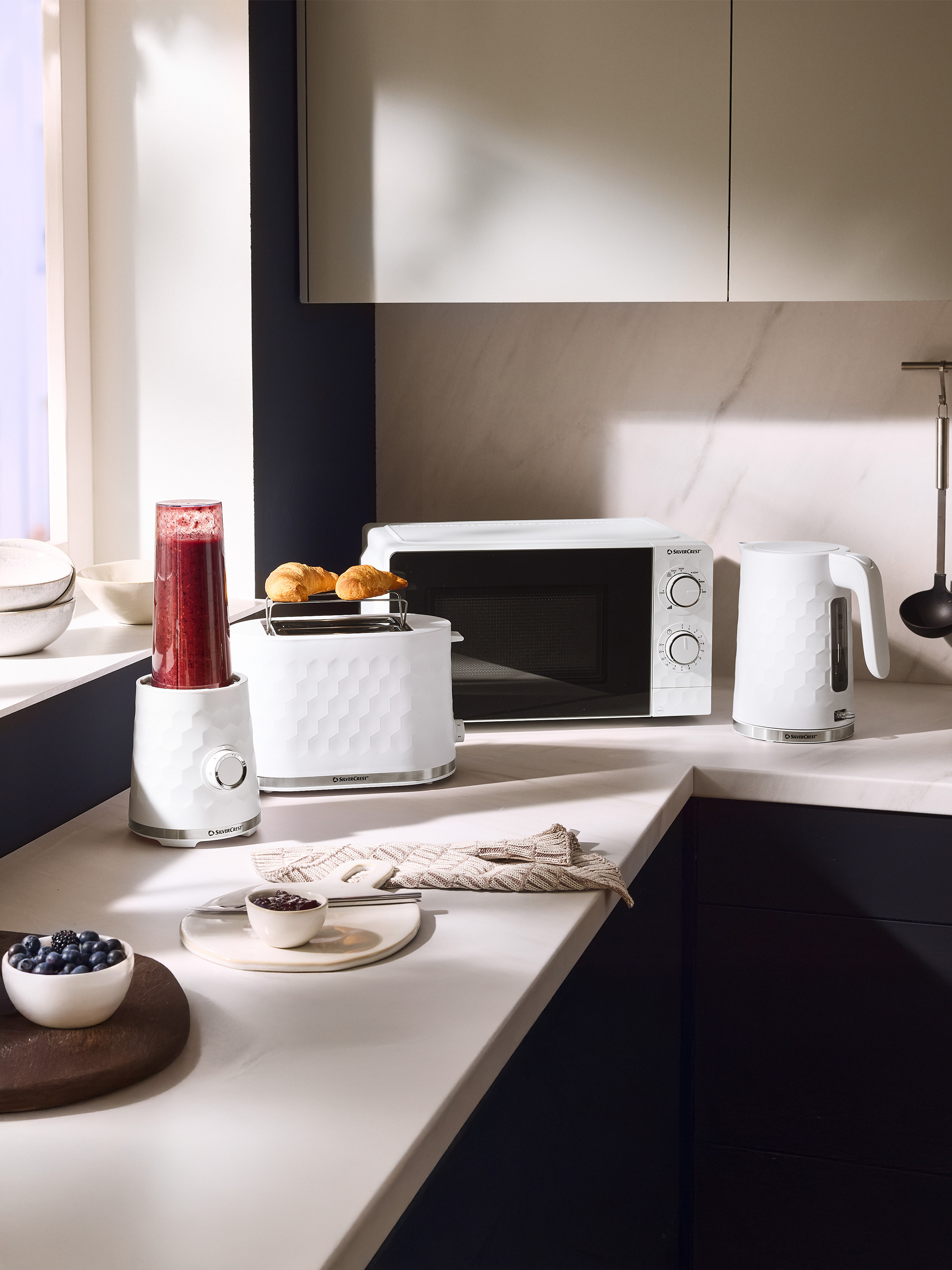 Witte keukenapparatuur: blender, broodrooster met croissants, magnetron en waterkoker.
