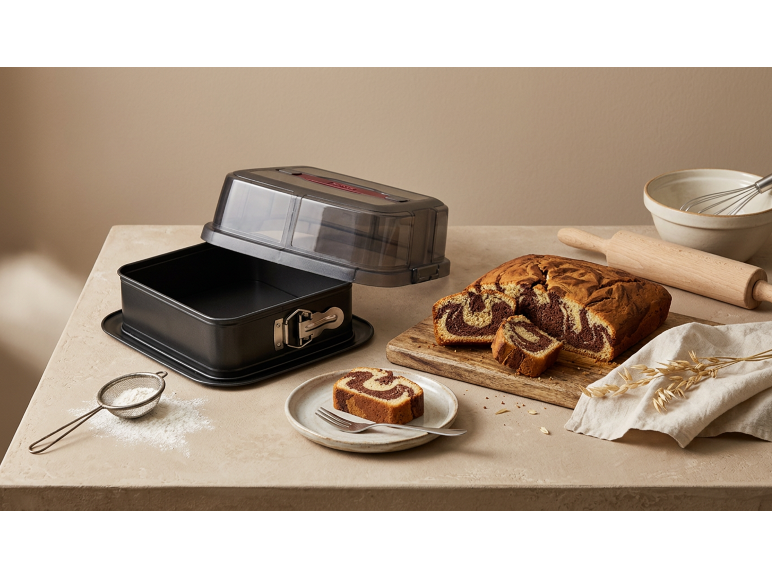 Marmercake in een broodvorm met transparant deksel, naast bakgerei.