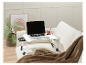Een laptop op een witte opklapbare tafel op een zachte bank.