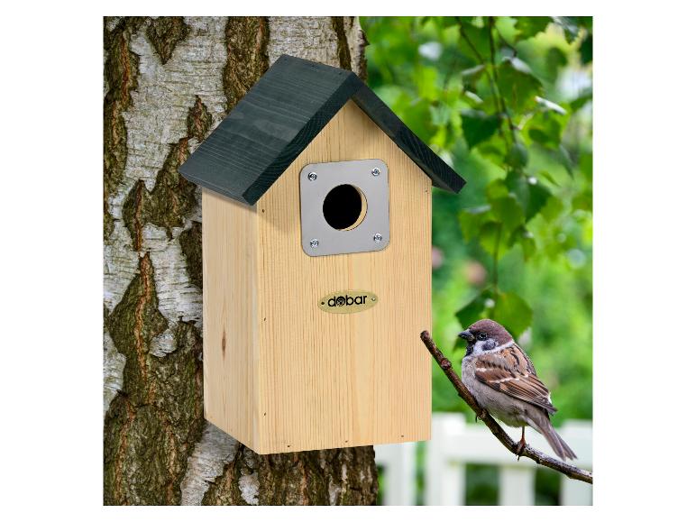 Houten vogelhuisje met groen dak, bevestigd aan een boom, met een vogel op een tak.