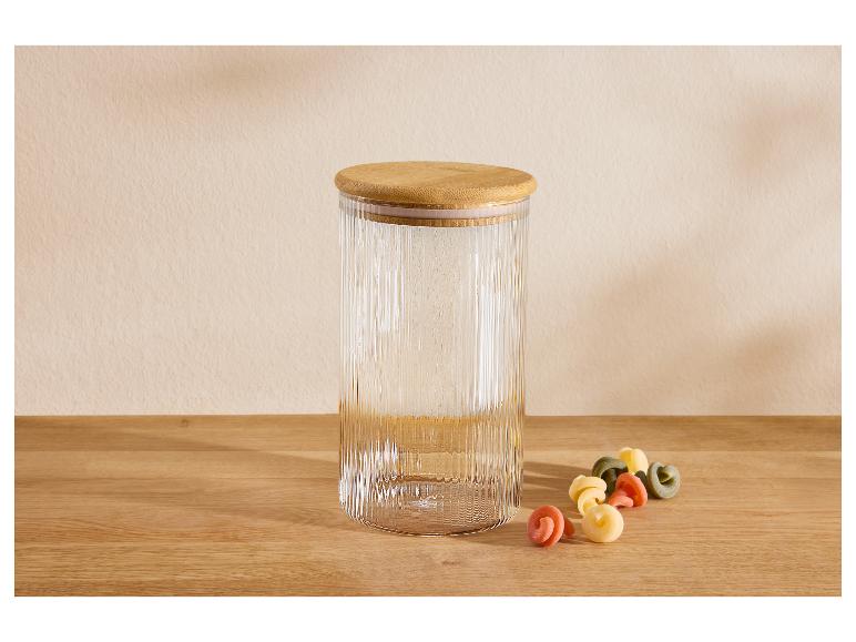 Glazen pot met bamboe deksel en gekleurde pasta op een houten tafel