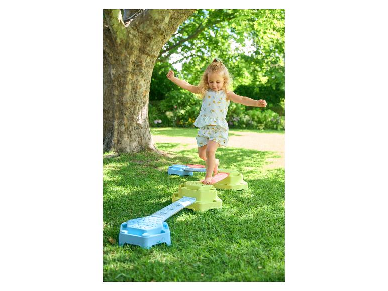 Meisje speelt met kleurrijke evenwichtsblokken in de tuin.