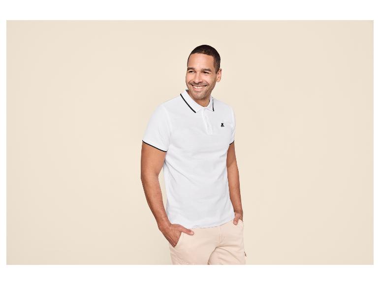 Man in een wit poloshirt met zwarte bies en lichtbeige cargoshorts.