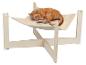 Rode kat slaapt vredig in een beige pluche hangmat met een licht houten frame.