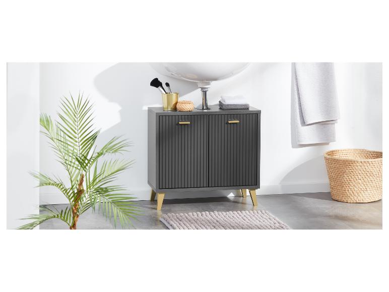 Een donkergrijs badkamerkastje met gouden poten en handgrepen staat op een kleed.