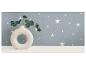Witte donutvaas met groene eucalyptus takken tegen een blauwe sterrenmuur.