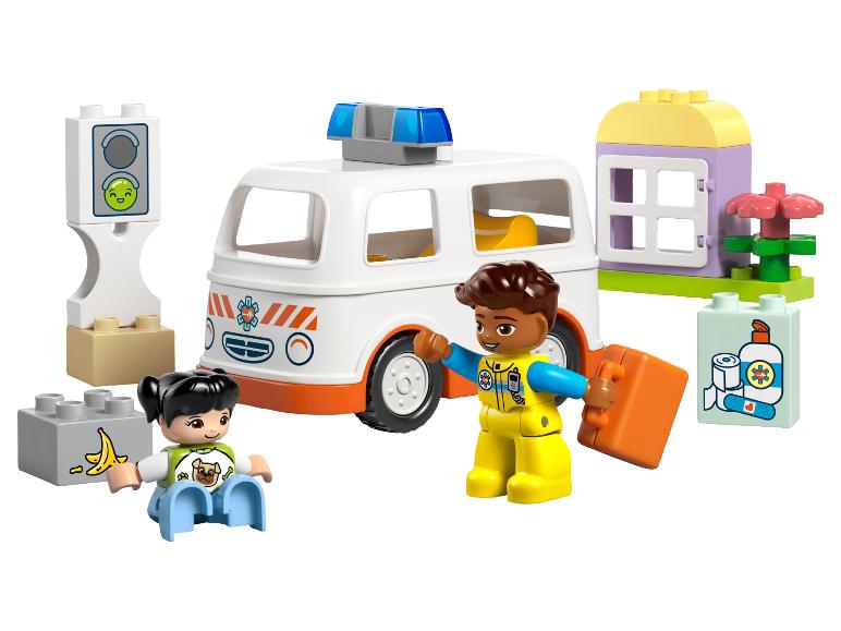 Speelgoedambulance, twee figuren en bouwblokken waaronder een huis en verkeerslicht.