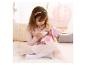 Meisje voedt babypop met fles, omringd door roze decor.