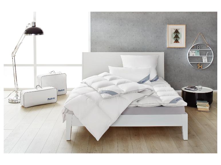 Moderne slaapkamer met wit bed, Balette dekbed en kussens, vloerlamp en wandplank.
