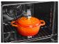 Oranje geëmailleerde braadpan in een oven.