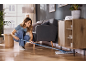 Vrouw maakt houten vloer schoon met een platte dweil in een moderne woonkamer.