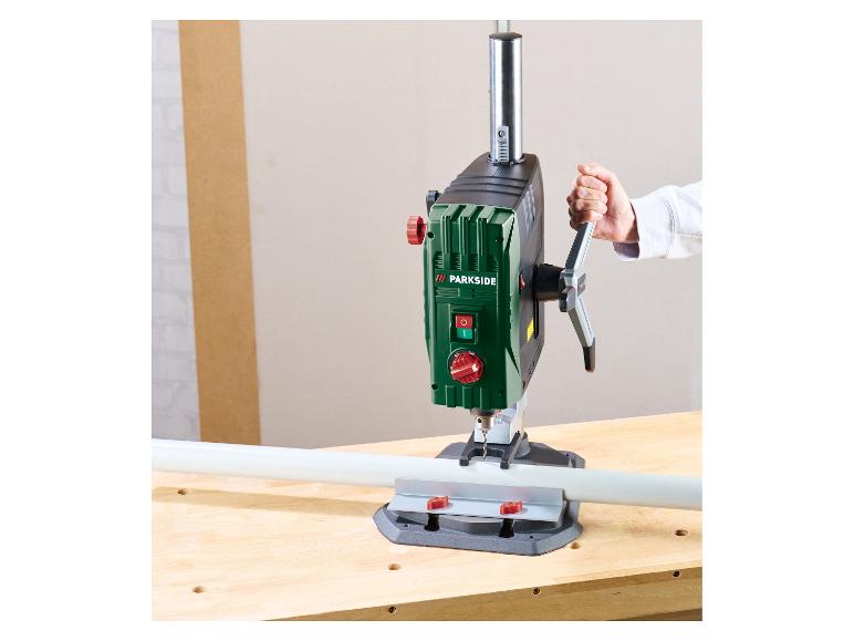 Kolomboormachine met een persoon die deze bedient en in een witte pijp boort op een werkbank.