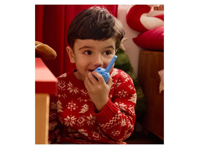 Een jongen in een kersttrui praat in een blauwe walkie-talkie.