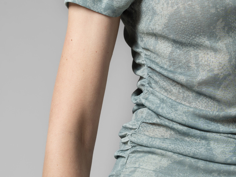 Een vrouw draagt een lichtblauw shirt met een gestreept patroon.