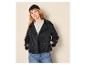 Vrouw in zwarte korte trenchcoat, grijs T-shirt, blauwe jeans en zwarte muts