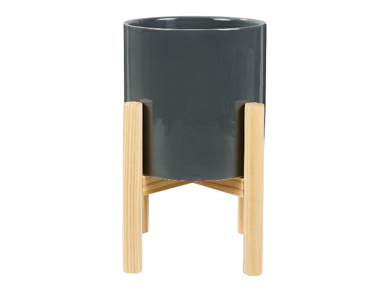 Een grijze bloempot op een houten standaard.